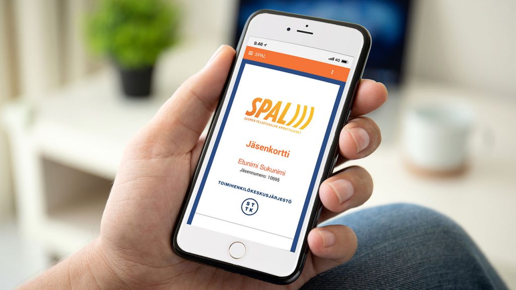 Mies pitää kädessään kännykkää, jossa on esillä SPALin jäsenmobiilin etusivu.